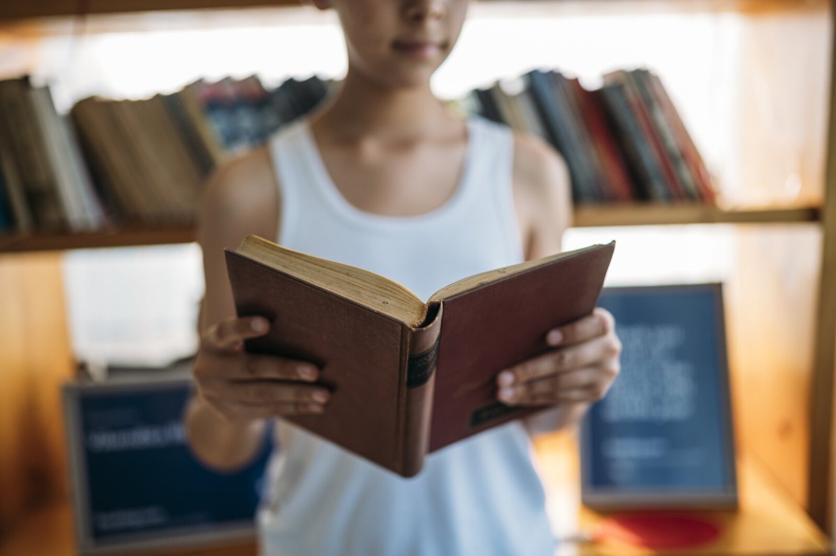 A young person reading a book in a library
